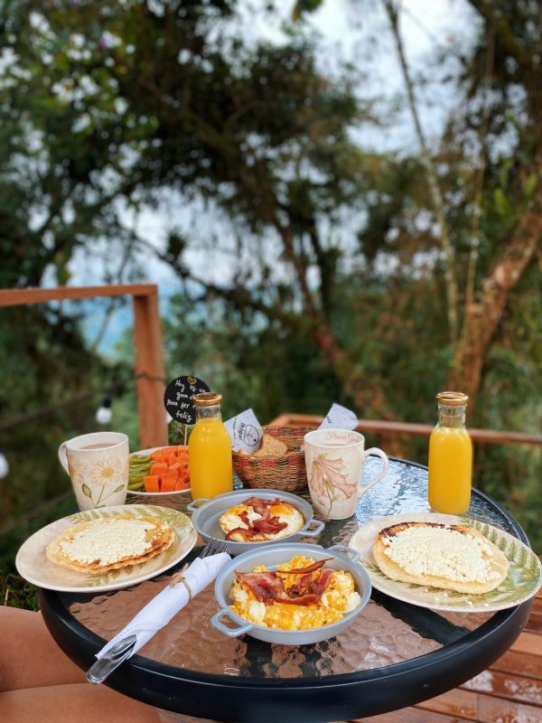 desayuno ikigai glamping, arepa con queso, huevos con tocino, jugo de naranja, chocolate, kiwi, papaya, tostaditas